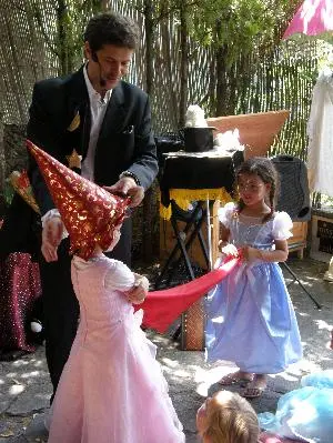 Danny le Magicien en spectacle pour un Anniversaire Enfant à Fréjus. Deux petites filles habillées en princesses avec un château de magiciennes tiennent un foulard magique dans les mains.